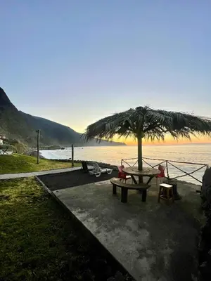 a picnic table with a umbrella next to the water at Casa do mar in São Vicente