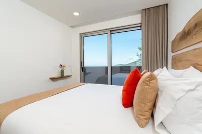 a bedroom with a white bed with red pillows at Bella Vista (Heated Pool & Private Parking) in Arco da Calheta