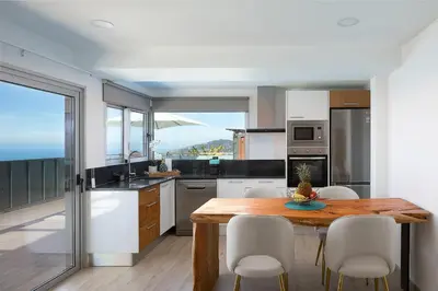 a kitchen with a wooden table and white appliances at Bella Vista (Heated Pool & Private Parking) in Arco da Calheta