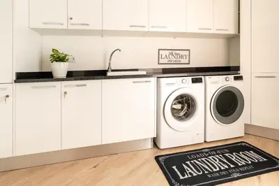 a kitchen with white cabinets and a washer and dryer at Bella Vista (Heated Pool & Private Parking) in Arco da Calheta
