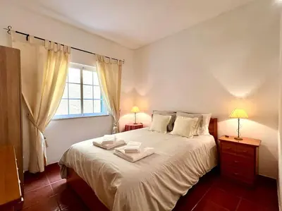 a bedroom with a large bed with two towels on it at Casa Rosado típica portuguesa in Barão de São João