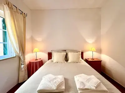 a bedroom with a large bed with two towels on it at Casa Rosado típica portuguesa in Barão de São João