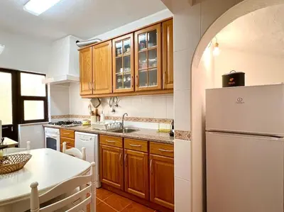 a kitchen with wooden cabinets and a white refrigerator at Casa Rosado típica portuguesa in Barão de São João