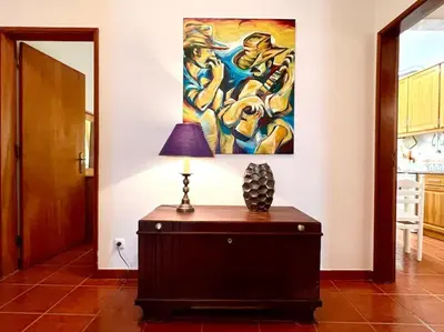 a lamp on a dresser in a room with a painting at Casa Rosado típica portuguesa in Barão de São João