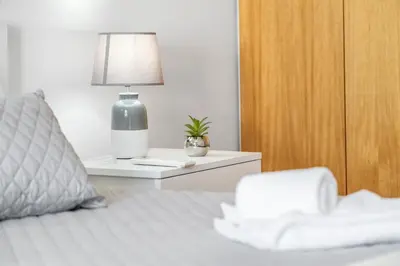 a white bedroom with a bed and a wooden door at Sun Hills Panoramic Views in Funchal
