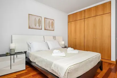 a bedroom with a white bed with a wooden cabinet at Sun Hills Panoramic Views in Funchal