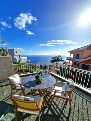 a patio with a table and chairs and the ocean at Sunshine Palace Madeira - Live Your Sunniest Dream! in Ponta do Sol