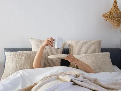 a person laying in bed holding a cup and a plate at Fisherhouse23 Comfortable holiday residence in Câmara de Lobos