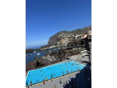a group of people in a swimming pool next to the ocean at Fisherhouse23 Comfortable holiday residence in Câmara de Lobos
