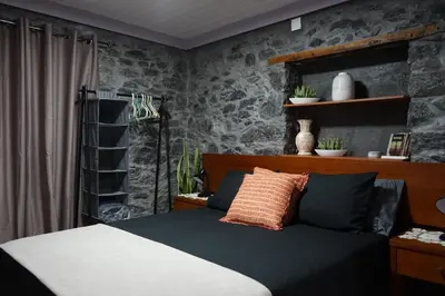 a bedroom with a bed and a stone wall at Casa do Lombo in Machico