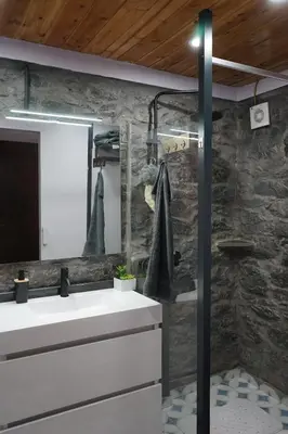 a bathroom with a white sink and a stone wall at Casa do Lombo in Machico