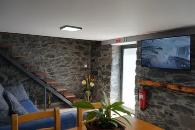 a living room with a tv on a stone wall at Casa do Lombo in Machico