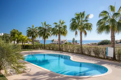 a swimming pool with palm trees and the ocean at Casa Lilou - Luxury Oceanview Penthouse in Lagos