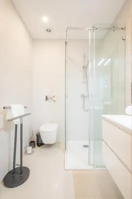 a white bathroom with a shower and a toilet at Casa Lilou - Luxury Oceanview Penthouse in Lagos