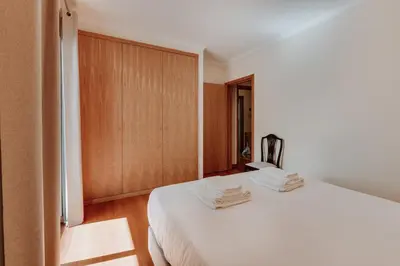 a bedroom with a white bed and wooden cabinets at Monumental Lidoview in Funchal