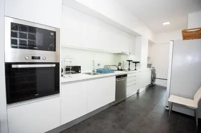 a kitchen with white cabinets and a black appliance at Santino Apartment in Caniço