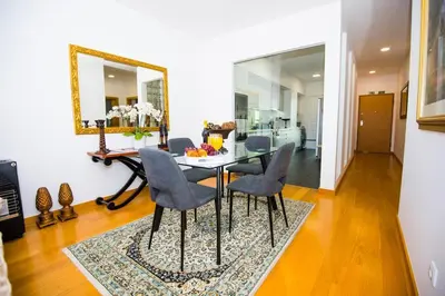 a dining room with a table and chairs and a mirror at Santino Apartment in Caniço