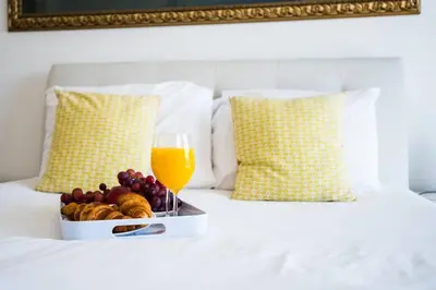 a tray of fruit and a glass of orange juice on a bed at Santino Apartment in Caniço