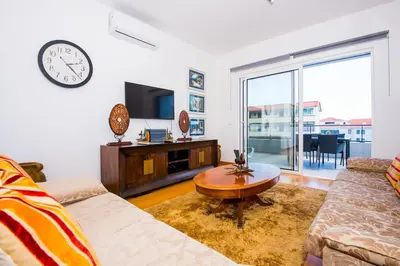 a living room with a couch and a clock on the wall at Santino Apartment in Caniço