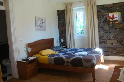 a bedroom with a bed and a stone wall at Herdade do Pedregal in Ponta do Pargo