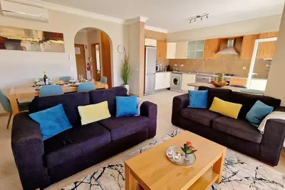 a living room with two couches and a kitchen at Deluxe 3 bedroom townhouse - Quinta da Atalaia in Lagos