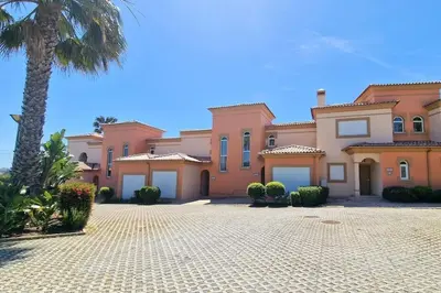 a large mansion with a palm tree and a driveway at Deluxe 3 bedroom townhouse - Quinta da Atalaia in Lagos