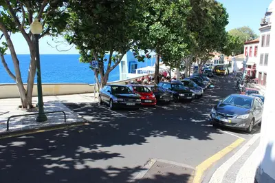 a row of cars parked on a street next to the ocean at Apartments Madeira Old Town in Funchal