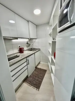 a small kitchen with white cabinets and a rug at Lido Branca by Olá Madeira in Funchal