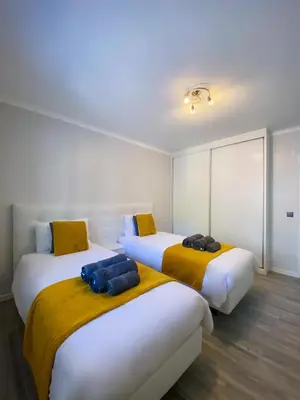 two beds in a room with white and yellow at Village Square Coastal Apartment 2F in Machico
