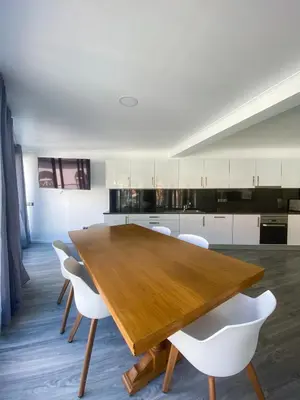a kitchen with a wooden table and white chairs at Village Square Coastal Apartment 2F in Machico