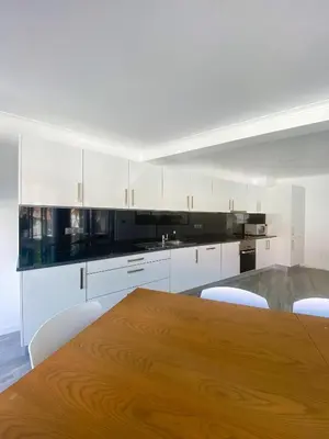 a kitchen with a wooden table and white cabinets at Village Square Coastal Apartment 2F in Machico