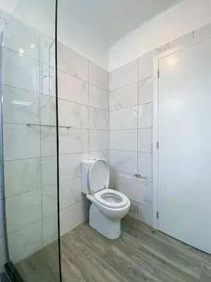 a bathroom with a toilet and a glass shower at Village Square Coastal Apartment 2F in Machico