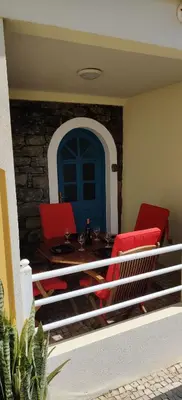 a balcony with red chairs and a table and a blue door at Harbour House in Paul do Mar