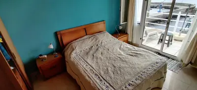 a bedroom with a bed with a blue wall and a window at Harbour House in Paul do Mar