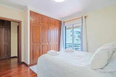 a bedroom with a large white bed and a window at Lido Costa do Sol in Funchal