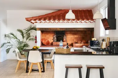 a kitchen with a fireplace and a table and chairs at A Casa Da Mãe in São Vicente