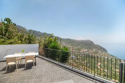 a balcony with a table and chairs and the ocean at Calheta Bay View House - Family and Group Residence in Arco da Calheta