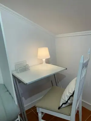 a desk with a lamp and a chair in a room at Refúgio do Seixal in Seixal