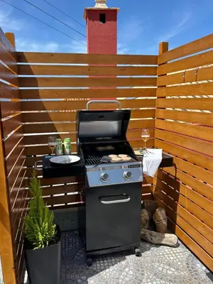 a grill on a patio with a wooden fence at Refúgio do Seixal in Seixal