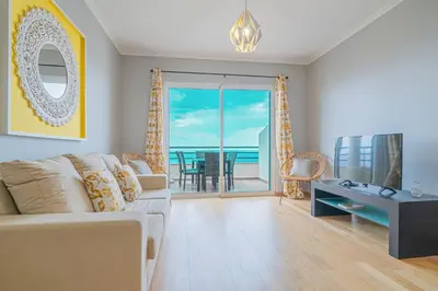 a living room with a couch and a television and a balcony at Ocean View Apartment in Caniço de Baixo in Funchal