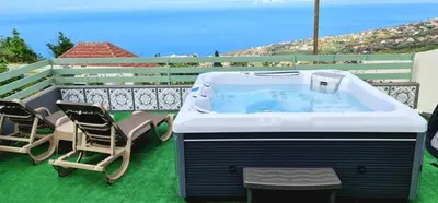 a hot tub on a patio with two chairs at Casa Monte de Paz in Calheta