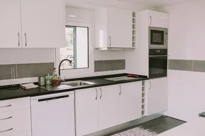 a white kitchen with a sink and a microwave at Casa Analino in Feiteiras