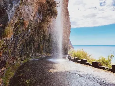 a mountain road with water spraying down the side of it at Figueira's House By the Atlantic in Ponta do Sol