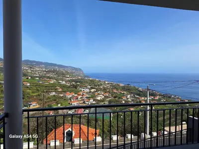 a view of a city and the ocean from a balcony at Figueira's House By the Atlantic in Ponta do Sol