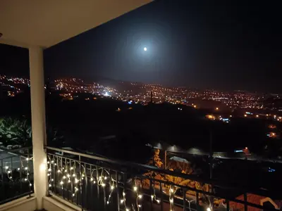 a view of a city at night from a balcony at Figueira's House By the Atlantic in Ponta do Sol