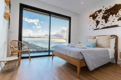 a bedroom with a bed and a large window at Villa Fénix in Câmara de Lobos