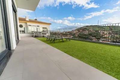 a balcony with a picnic table and a view of a city at Villa Fénix in Câmara de Lobos