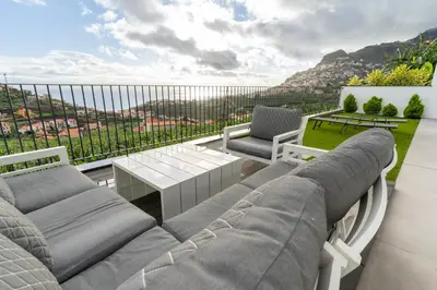 a patio with a couch and a table on a balcony at Villa Fénix in Câmara de Lobos