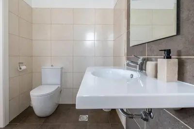 a bathroom with a white sink and a toilet at Luxury Haven: Heated Pool, AC & Sun in Ponta do Sol