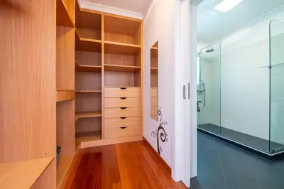 a walk in closet with wooden shelves and a glass shower at Luxury Haven: Heated Pool, AC & Sun in Ponta do Sol